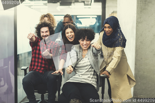 Image of multiethnics business team racing on office chairs