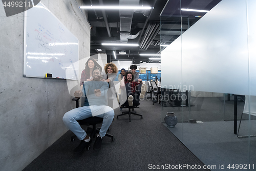 Image of multiethnics business team racing on office chairs