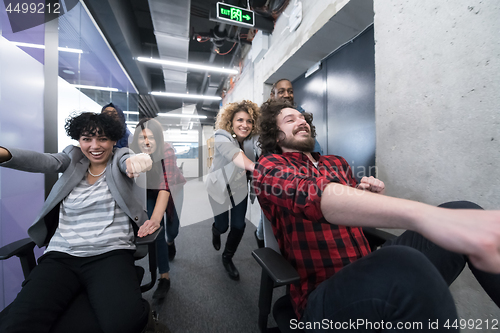 Image of multiethnics business team racing on office chairs