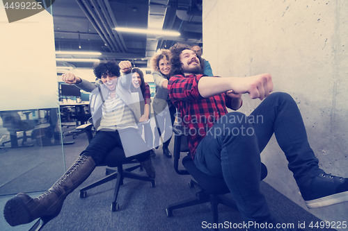 Image of multiethnics business team racing on office chairs