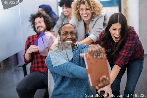 Image of multiethnics business team racing on office chairs