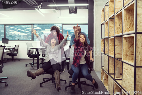 Image of multiethnics business team racing on office chairs