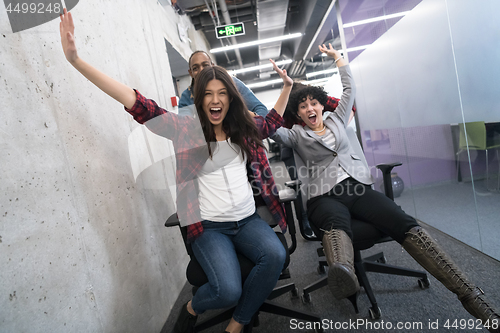 Image of multiethnics business team racing on office chairs