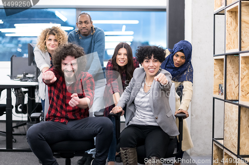 Image of multiethnics business team racing on office chairs