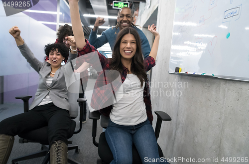 Image of multiethnics business team racing on office chairs