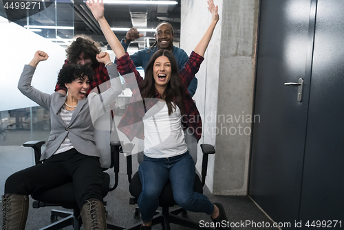 Image of multiethnics business team racing on office chairs