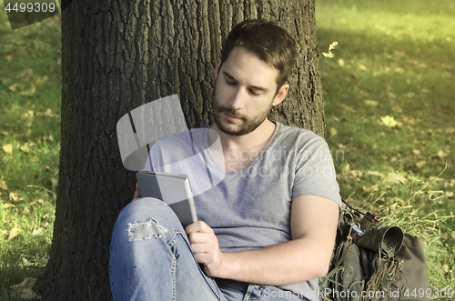 Image of Young man reading e-book