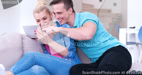Image of couple relaxing at  home with tablet computers