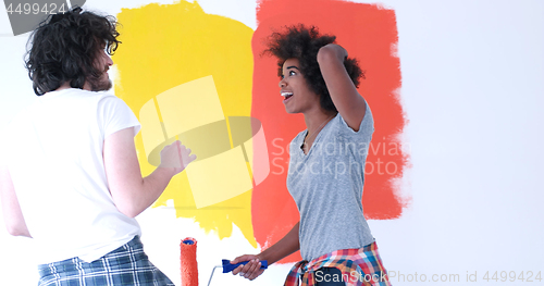 Image of multiethnic couple painting interior wall