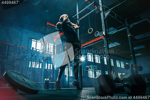 Image of Fit young man lifting barbells working out in a gym