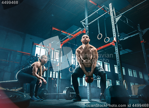 Image of Fit young man lifting barbells working out in a gym