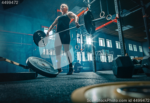 Image of Fit young woman lifting barbells working out in a gym