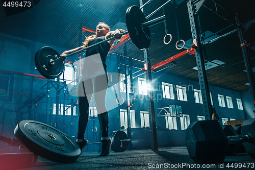Image of Fit young woman lifting barbells working out in a gym