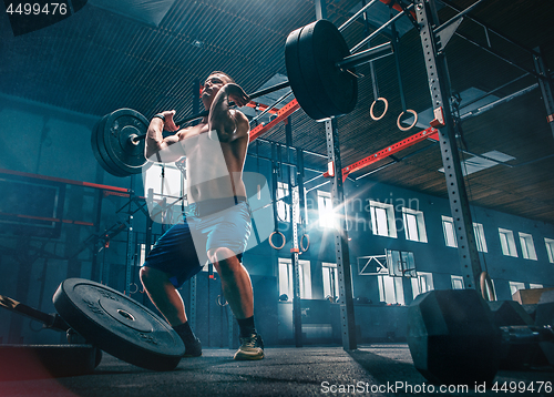 Image of Fit young man lifting barbells working out in a gym