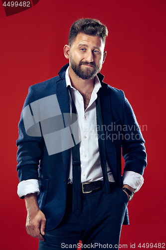 Image of The happy business man standing and smiling against red background.