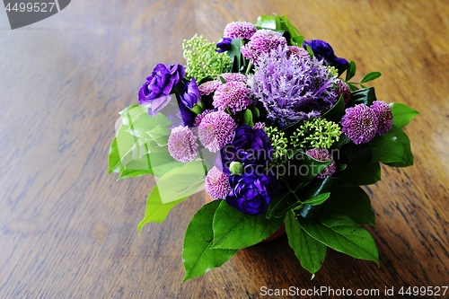 Image of bouquet of flowers in a ceramic vase on a wooden table
