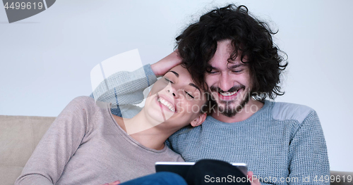 Image of couple relaxing at  home with tablet computers