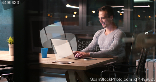 Image of man working on laptop in dark office