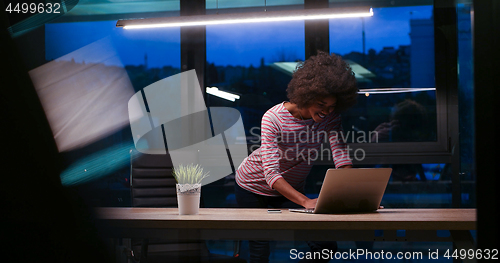 Image of black businesswoman using a laptop in night startup office