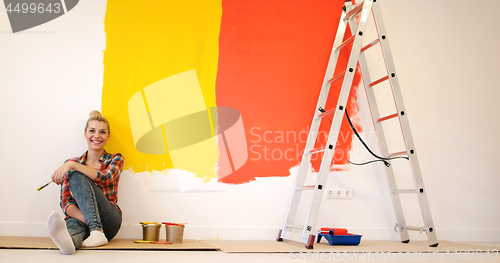 Image of young female painter sitting on floor