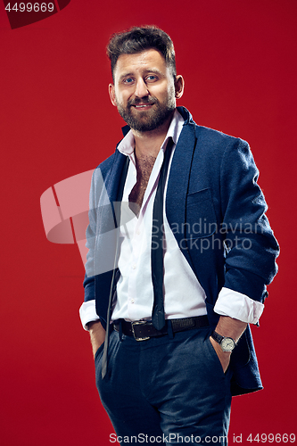 Image of The happy business man standing and smiling against red background.