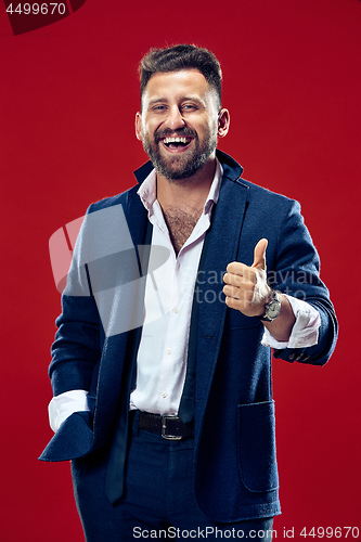 Image of The happy business man standing and smiling against red background.