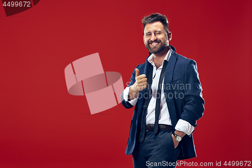 Image of The happy business man standing and smiling against red background.