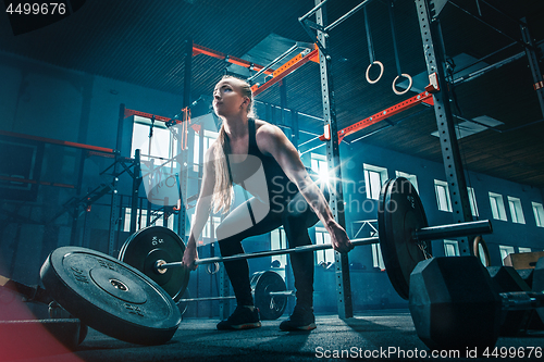 Image of Fit young woman lifting barbells working out in a gym