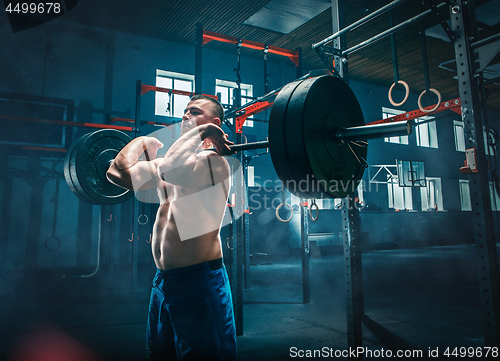 Image of Fit young man lifting barbells working out in a gym