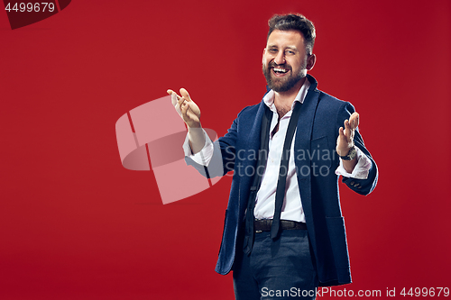 Image of The happy business man standing and smiling against red background.