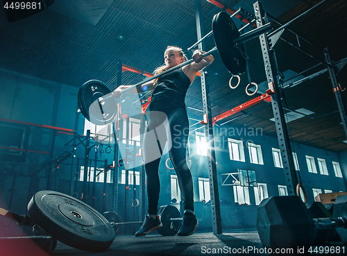 Image of Fit young woman lifting barbells working out in a gym