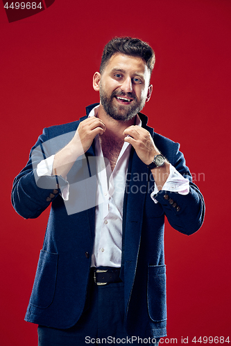 Image of The happy business man standing and smiling against red background.