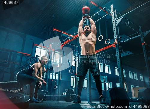 Image of Fit young man lifting barbells working out in a gym