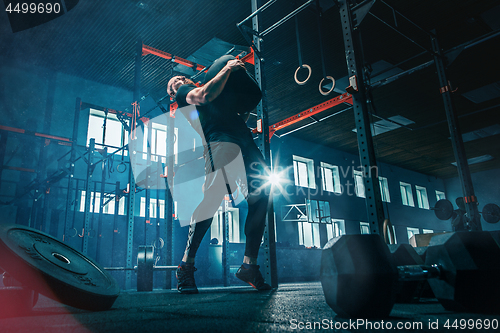 Image of Fit young man lifting barbells working out in a gym