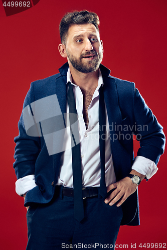 Image of The happy business man standing and smiling against red background.