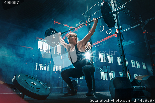 Image of Fit young woman lifting barbells working out in a gym