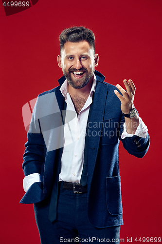 Image of The happy business man standing and smiling against red background.