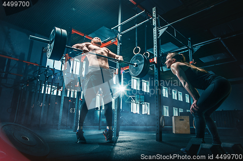 Image of Fit young man lifting barbells working out in a gym