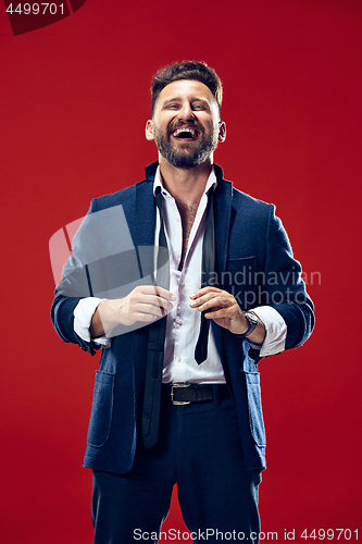Image of The happy business man standing and smiling against red background.