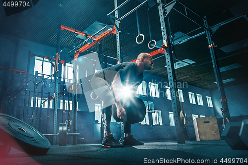 Image of Fit young man lifting barbells working out in a gym