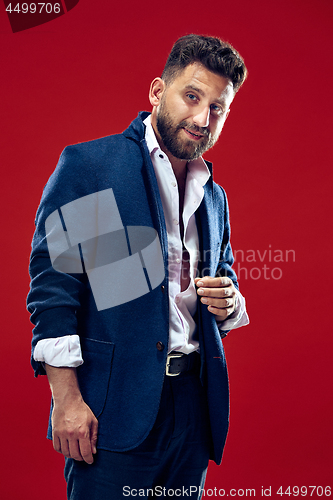 Image of The happy business man standing and smiling against red background.
