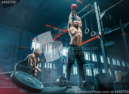 Image of Fit young man lifting barbells working out in a gym