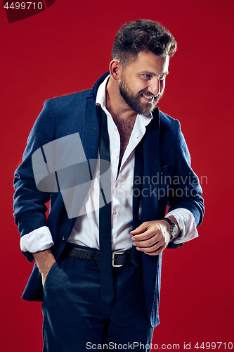 Image of The happy business man standing and smiling against red background.