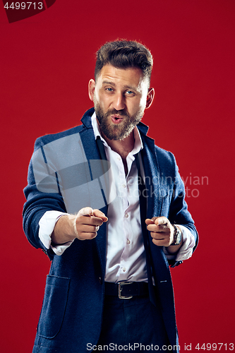 Image of The happy business man point you and want you, half length closeup portrait on red background.