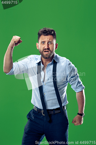 Image of The young emotional angry man screaming on green studio background