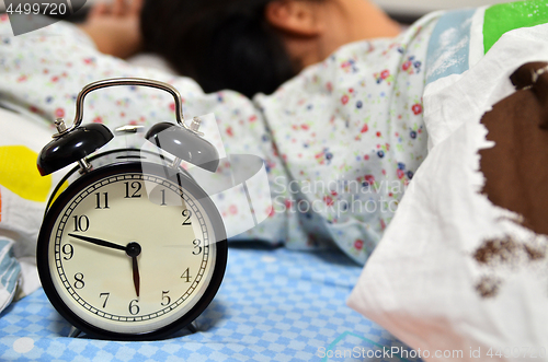 Image of Pretty girl sleeping on the background of a retro alarm clock