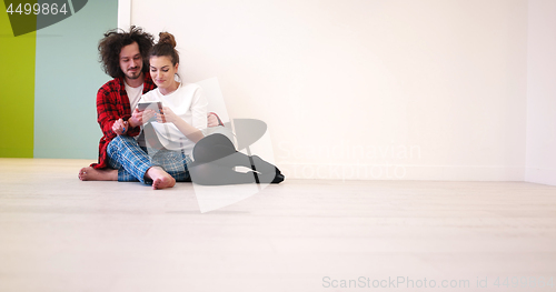 Image of Young Couple using digital tablet on the floor