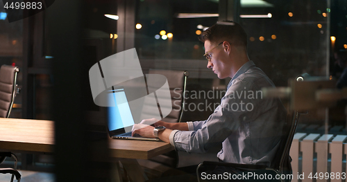 Image of man working on laptop in dark office