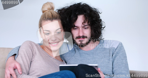 Image of couple relaxing at  home with tablet computers