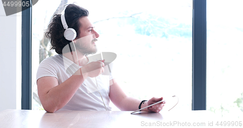 Image of young man listenig music on tablet at home